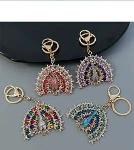 Detail view of four peacock keychains with colorful rhinestones and golden alloy finish