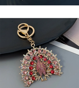 Close-up of golden peacock keychain with sparkling pink and red rhinestones and lobster clasp