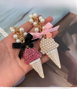 Détail de porte-clés crème glacée avec strass roses, perles et nœuds sur fond doux