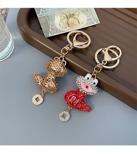 Close-up of golden and red lucky toad keychains with traditional coin charms on a plate