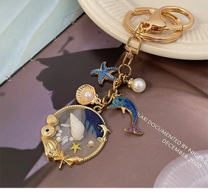 Detailed close-up of a gold ocean theme keychain with dolphin and starfish charms
