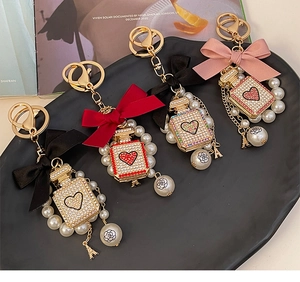 Detailed view of diamond perfume bottle keychains with pearl charms and silk bows