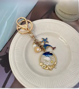 Detail of blue dolphin and starfish keychain with pearl shell charm on a golden clasp