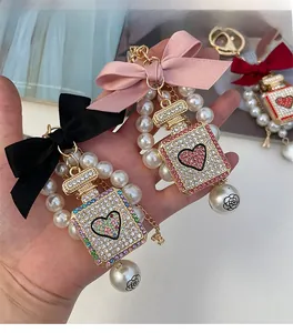 Close-up of pearl perfume bottle keychains with rhinestone heart and bow details