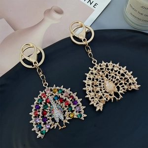 Sparkling peacock metal keychain with colorful rhinestones on a matte black display