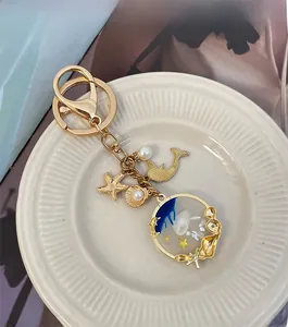 Detail of golden ocean-themed keychain with dolphin, shell, and resin star charms