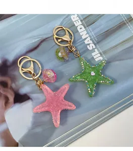 Detail of pink and green resin star keychains with rhinestone edges and shell charms