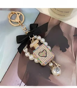 Close-up of pearl perfume bottle keychain with crystal heart and black satin bow
