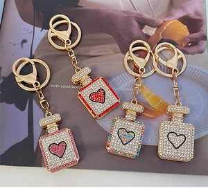 Close-up of heart perfume bottle keychains with colorful rhinestones and gold hooks
