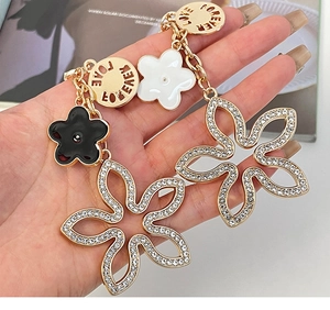 Macro detail of dangling clover earrings with crystal rhinestones and Forever Love engraving