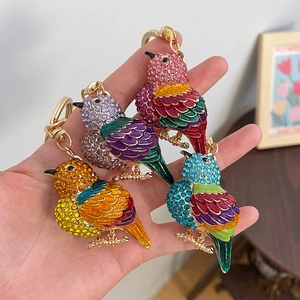 Handgehaltenes Set aus vier Cartoon-Vogel-Schlüsselanhängern mit bunten Strasssteinen