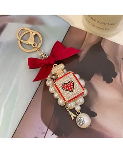 Detail of pearl keychain with red bow and rhinestone-encrusted perfume bottle charm