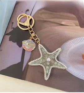 Detail of starfish and shell keychain with sparkling rhinestones on golden metal ring