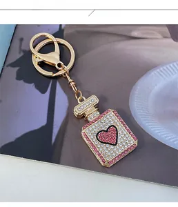 Detailed close-up of crystal-encrusted perfume bottle keychain with pink heart on a gold base