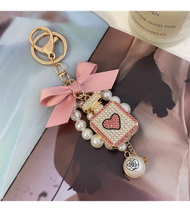 Detail of pink bow and pearl perfume bottle keychain with crystal rhinestone heart