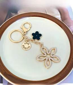 Detailed close-up of lucky four-leaf clover keychain with rhinestones and LOVE FOREVER tag