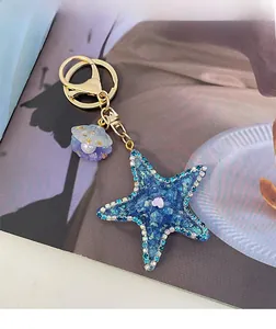 Close-up of a blue starfish keychain with rhinestones and a purple shell with pearl detail