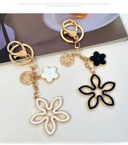 Detail of gold metal keychains with black and white clover charms and LOVE FOREVER engraving