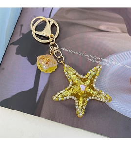 Macro detail of yellow resin starfish keychain with rhinestones and gold lobster clasp