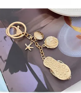 Golden keychain with seashell and starfish charms plus a heart pattern flip-flop detail