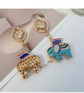 Detailed view of two Thai elephant keychains with gold filigree and blue rhinestones
