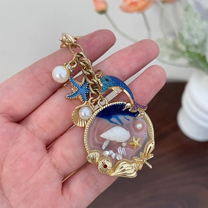 Golden keychain featuring blue dolphin, starfish, and resin ocean beach charms with pearls