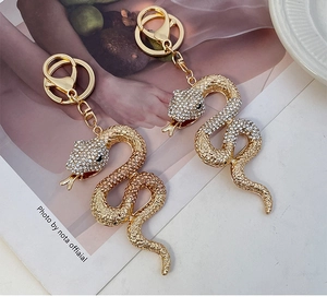 Vue détaillée de deux pendentifs serpent dorés sertis de cristaux brillants sur anneaux