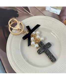 Detail of luxury cross keychain with black crystals, silk bow and white pearls