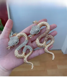 Détail macro de pendentifs serpent avec cristaux scintillants et finition dorée