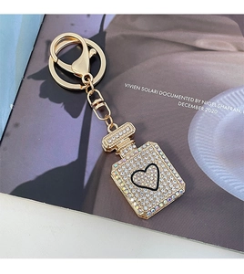 Detailed view of luxury heart perfume bottle keychain with white crystals and gold finish