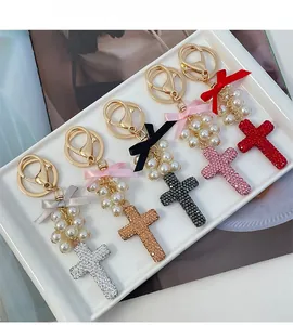 Detail of five rhinestone cross keychains with pearls and bows in multiple colors
