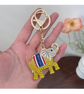 Détail d'un porte-clés éléphant thaïlandais doré orné de strass jaunes et d'une inscription