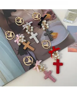 Detailed display of rhinestone cross and pearl bow keychains in five different colors