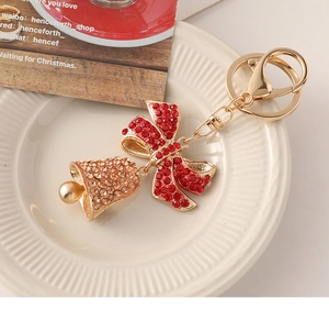 Detailed macro of golden Christmas bell keychain with champagne rhinestones and red bow
