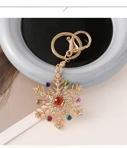 Détail d'un porte-clés flocon de neige doré avec des strass multicolores et un centre rouge