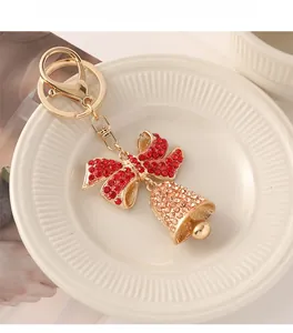 Detail of Christmas bell keychain with red bow and champagne rhinestones on ceramic