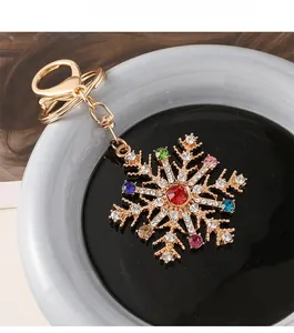 Vue détaillée du porte-clés flocon de neige doré avec strass colorés dans un récipient