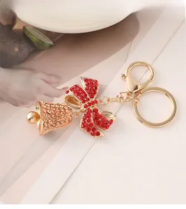 Detail of a sparkling Christmas bell and red bow keychain with golden lobster clasp