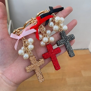 Cross keychain set with sparkling rhinestones, pearls, and bows in gold, red, and black