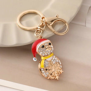 Golden Christmas penguin keychain with rhinestones and Santa hat on a beige plate