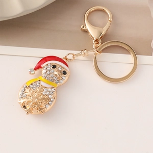 Golden Christmas snowman keychain with red hat and sparkling rhinestones on light background