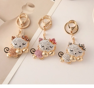 Close-up of three lying cat keychains with rhinestones in gold, pink and silver