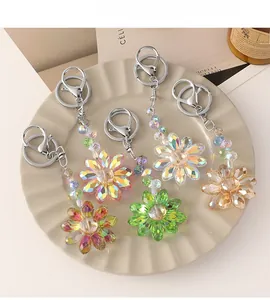 Five colorful crystal sunflower keychains with faceted petals in a white ceramic dish