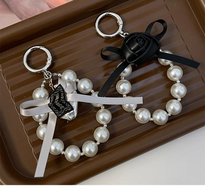 Detail of pearl keychains with ribbon bows, leather roses and silver metal ring clasps