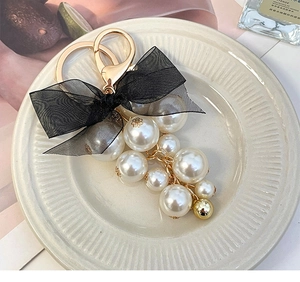 Detail of elegant keychain with black sheer bow and gradient imitation pearls decoration