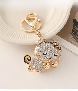 Close-up of golden cat keychain with white rhinestones and cute enamel bow detail