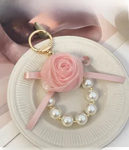 Detailed view of pink fabric rose keychain with pearls and golden lobster clasp hardware
