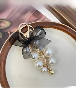Detailed view of elegant black mesh bow keychain with imitation pearls and gold bell accessory