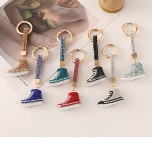 Dettaglio ravvicinato di portachiavi a forma di sneaker con strass colorati e ganci dorati