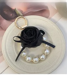 Detailed macro view of black chiffon rose keychain with pearls and golden spring clasp